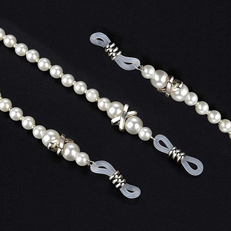 two necklaces with white pearls and silver beads on a black background, one is tied up