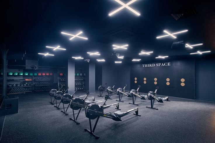 an empty gym with rows of treadmills in the middle and lights on the ceiling