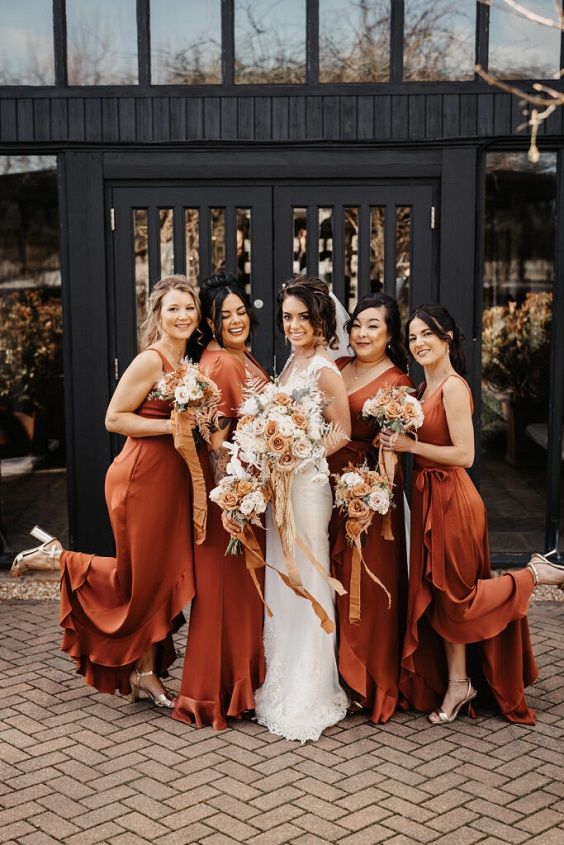 a group of women standing next to each other in front of a black fence with flowers