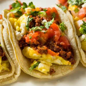 three tacos are sitting on a plate with salsa and other toppings around them