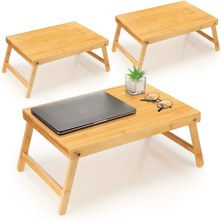 three small wooden tables with laptops and glasses on each table, along with a potted plant