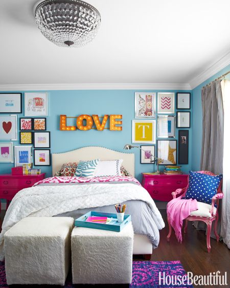 a bedroom with blue walls, pink furniture and pictures on the wall above the bed