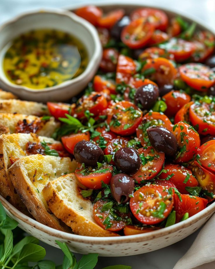 a bowl filled with bread, olives and tomatoes