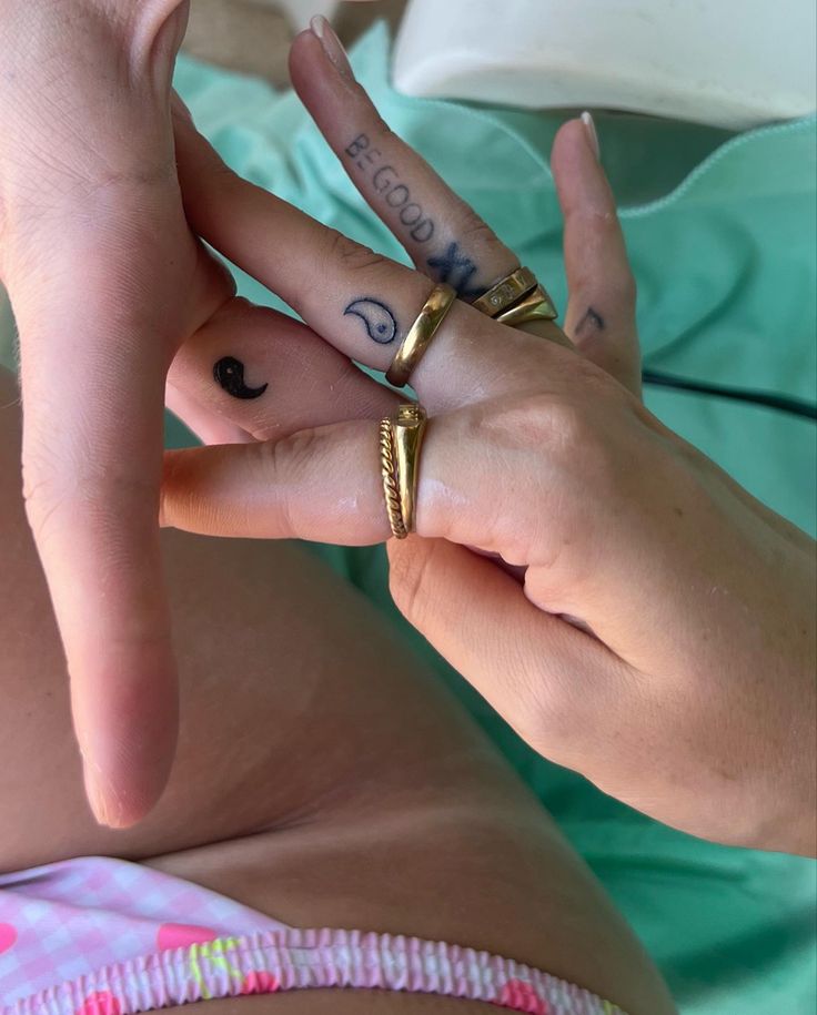 two people with tattoos on their fingers touching each other