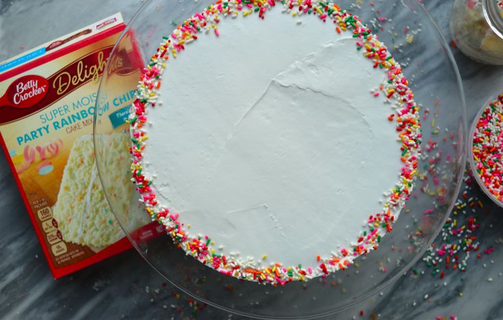 a frosted cake with sprinkles next to a package of doughnuts