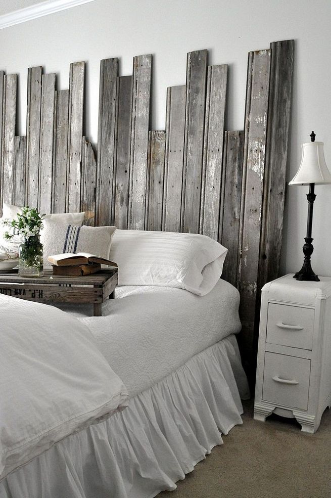 a bed with white linens and wooden headboard made out of pallet boards