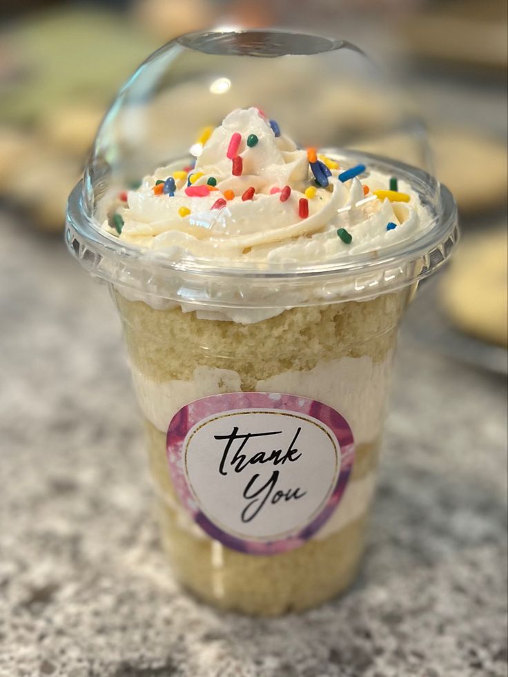 a cup filled with white frosting and sprinkles on top of a counter