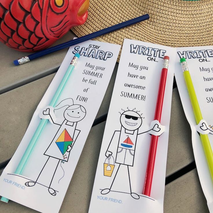 two bookmarks with writing on them sitting next to a straw hat and pencils