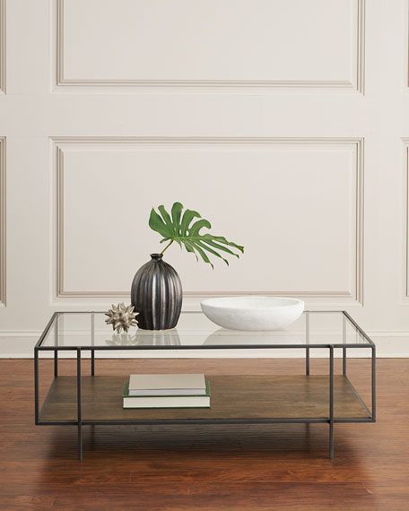 a black and white vase sitting on top of a glass table next to a book