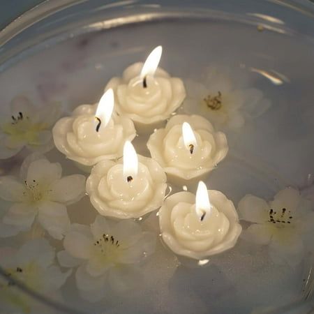 four candles are floating in water with white flowers