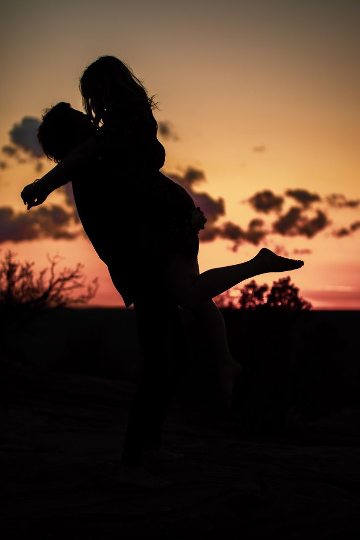 the silhouette of two people in front of a sunset