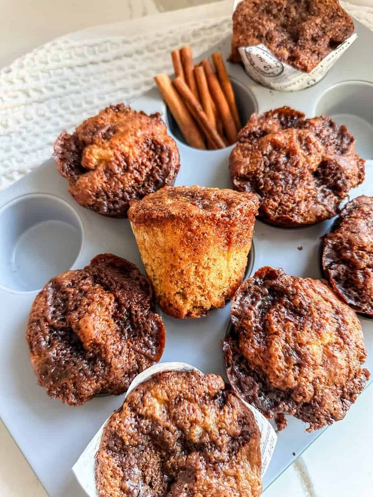 several muffins on a tray with cinnamon sticks