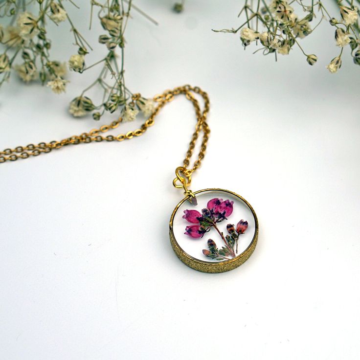 "Real pressed Heather Flowers are encased in jewelry grade resin within this stunning stardust raw brass circle bezel. The setting has a textured finish, which gives just a bit of extra dazzle. Attached to a matching 18\" chain and measures 3/4\" diameter. Hangs on a labelled card, easy for gifting!" Gold Brass Jewelry With Pressed Flowers, Pressed Flowers Yellow Gold Jewelry, Rose Gold Jewelry With Pressed Flowers In Round Pendant, Yellow Gold Jewelry With Pressed Flowers In Round Pendant, Yellow Gold Round Pendant With Pressed Flowers, Botanical Style Gold Resin Jewelry, Resin Round Pendant Jewelry With Birth Flower, Pressed Flowers Round Pendant Jewelry Gift For Her, Resin Birth Flower Round Pendant Jewelry