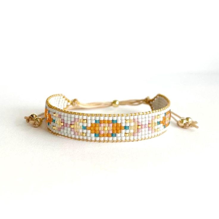 the beaded bracelet is made with white, orange and yellow beads on a gold plated