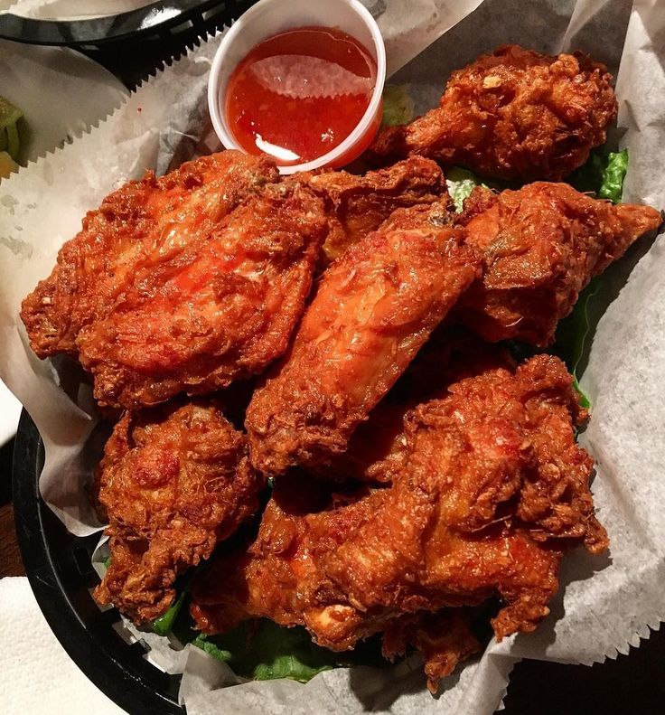 fried chicken with lettuce and ketchup served on paper wrappers next to dipping sauce