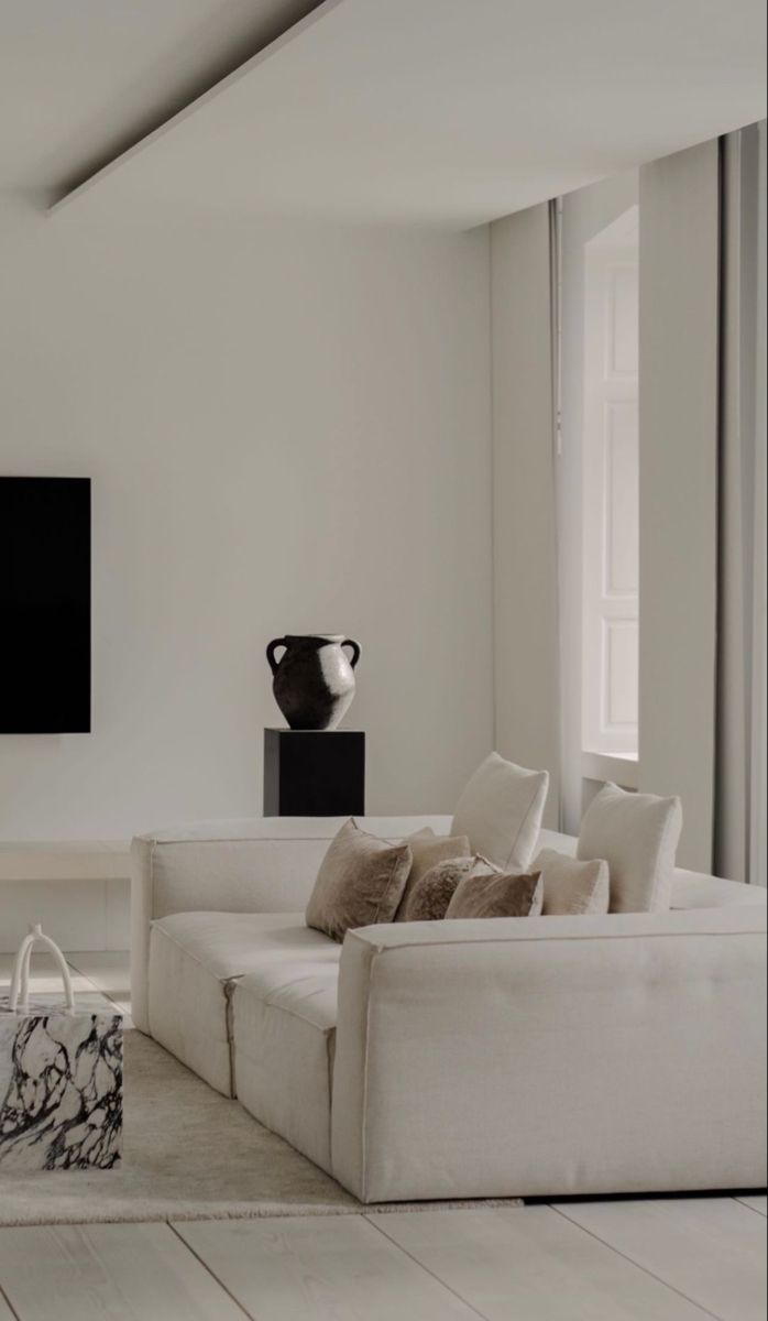 a living room with white furniture and a large flat screen tv mounted on the wall