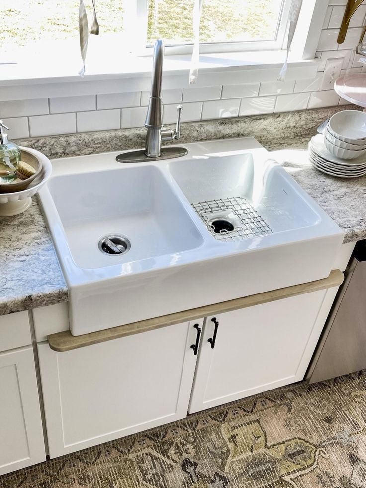 a white kitchen sink sitting on top of a counter next to a dishwasher