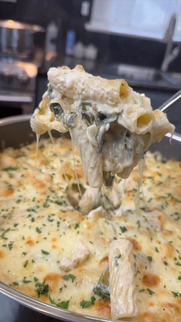 a spoon full of food being lifted from a casserole dish with cheese and spinach