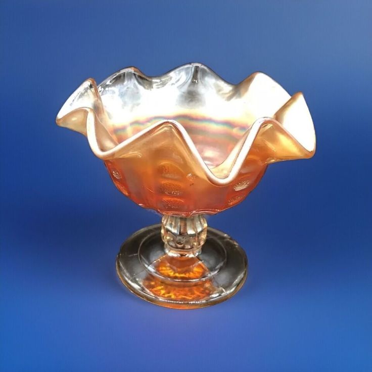 a glass bowl sitting on top of a metal saucer in front of a blue background