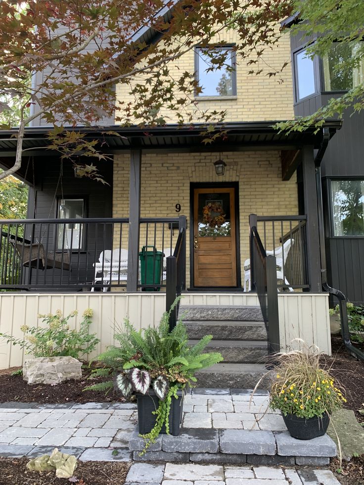 the front entrance of a house with steps leading up to it and potted plants