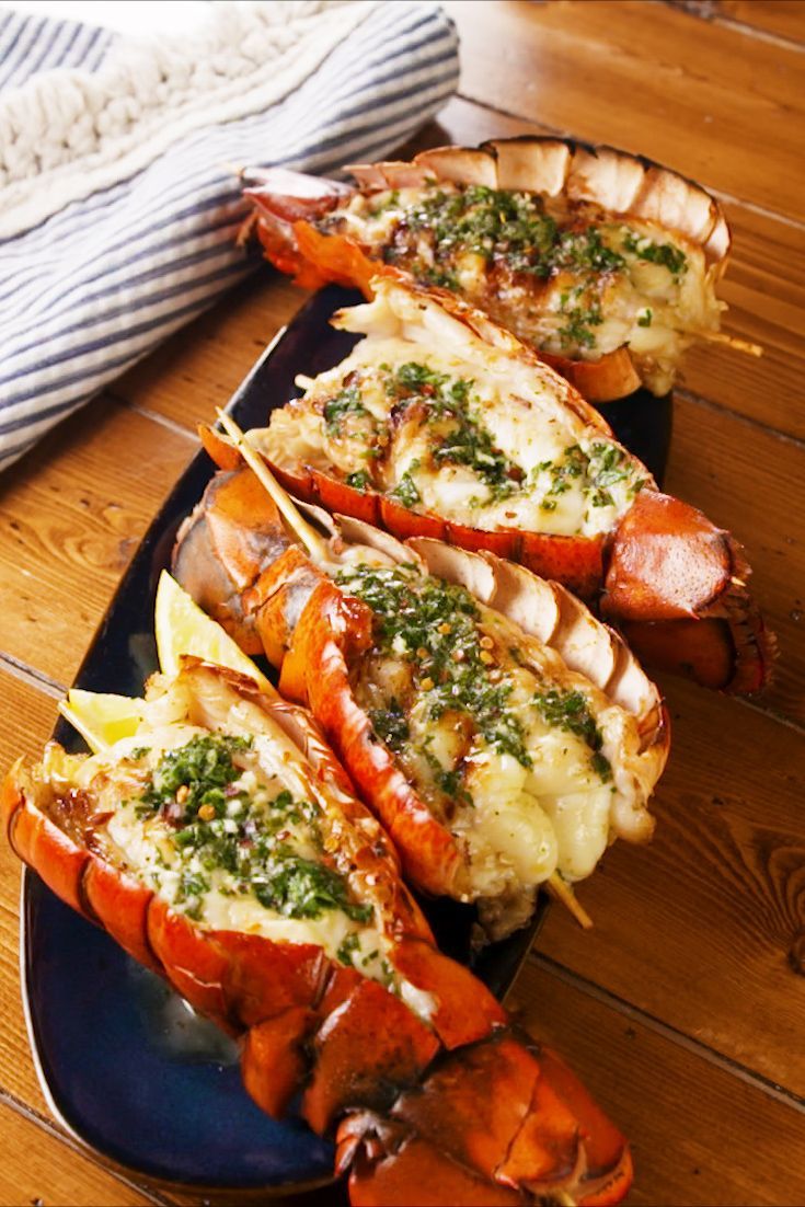 four lobsters on a black plate with cheese and parsley garnishes