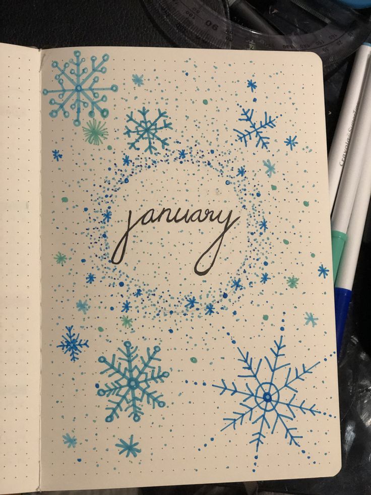 an open notebook with blue snowflakes and the word january written in cursive writing