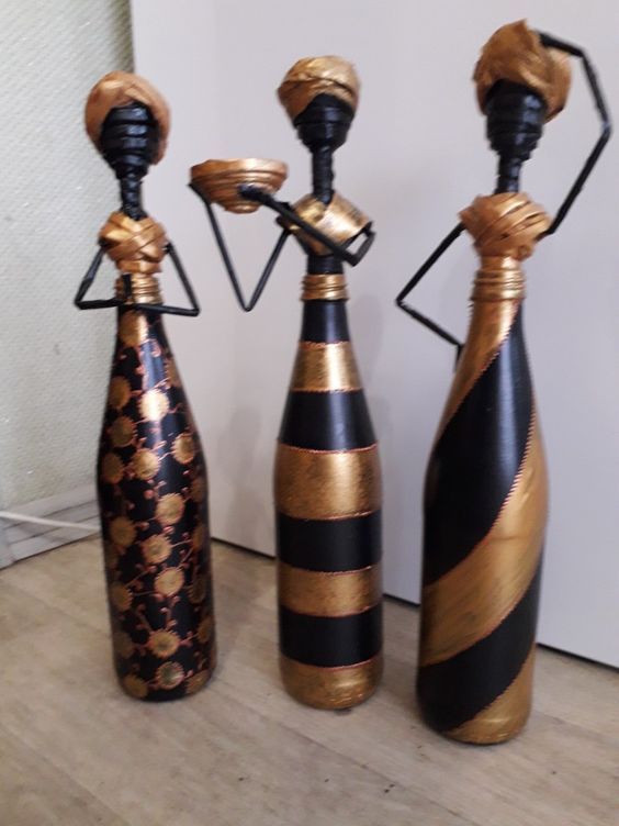 three black and gold vases sitting next to each other on a wooden floor in front of a white wall