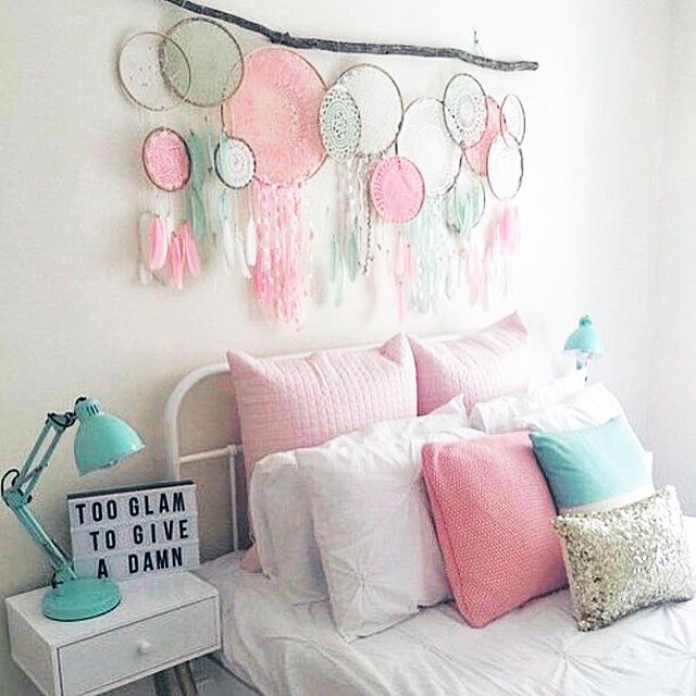 a white bed with pink and green pillows on it's headboard next to a window