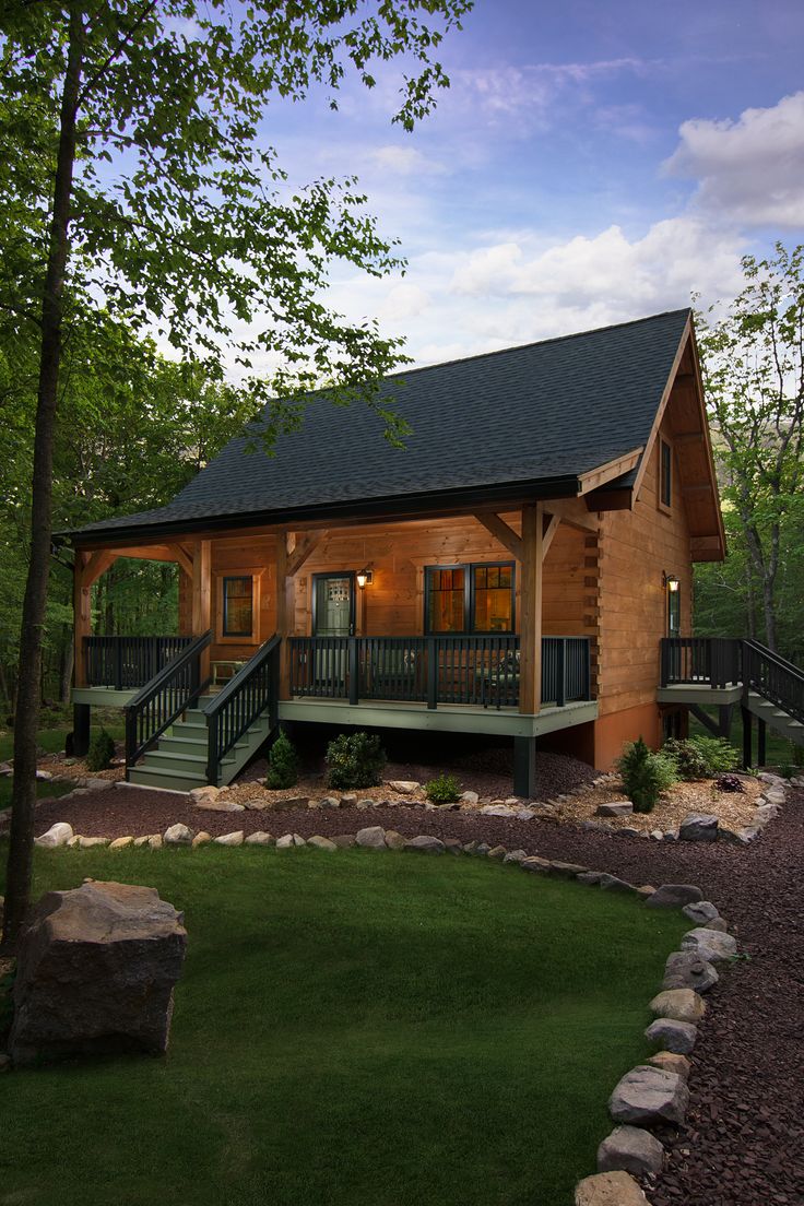 a log cabin sits in the middle of a wooded area with stairs leading up to it