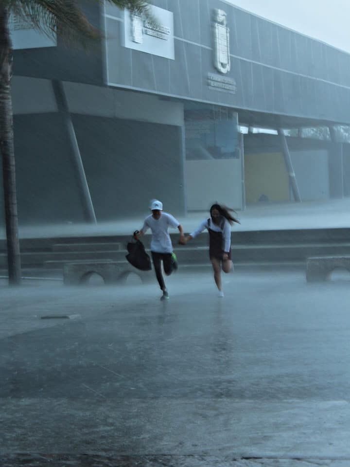 two people running in the rain holding hands