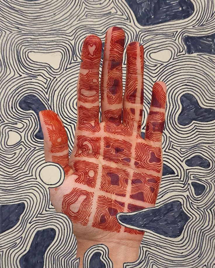 a person's hand with red and white designs on it, in front of an abstract background