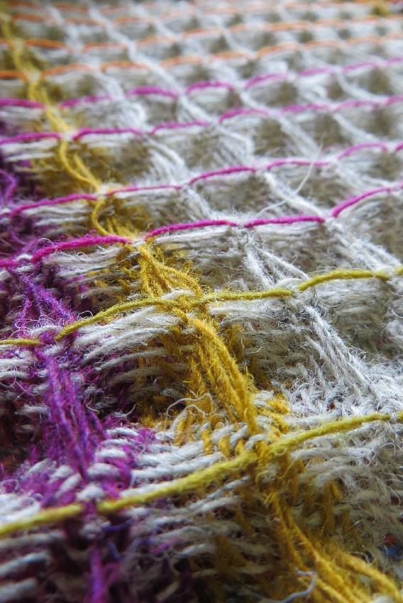 a close up view of a crocheted blanket with different colored yarns on it