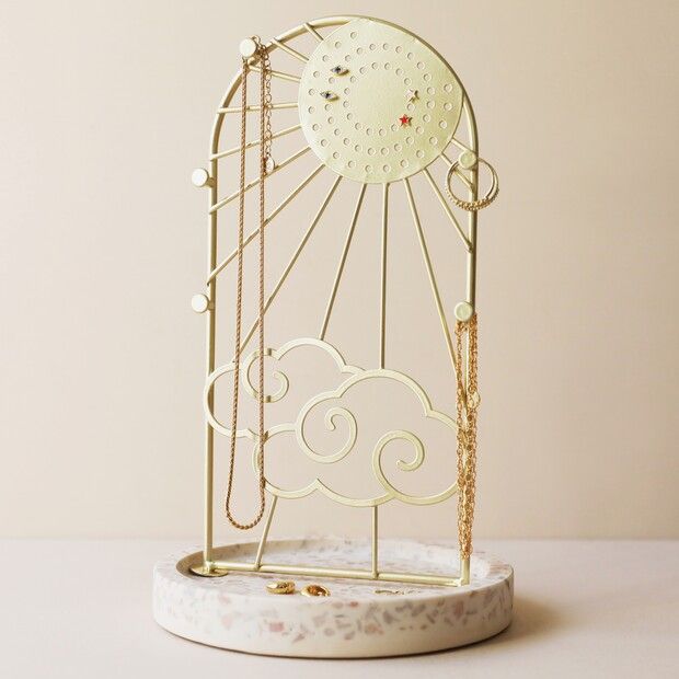 a white clock sitting on top of a table next to a shelf filled with jewelry