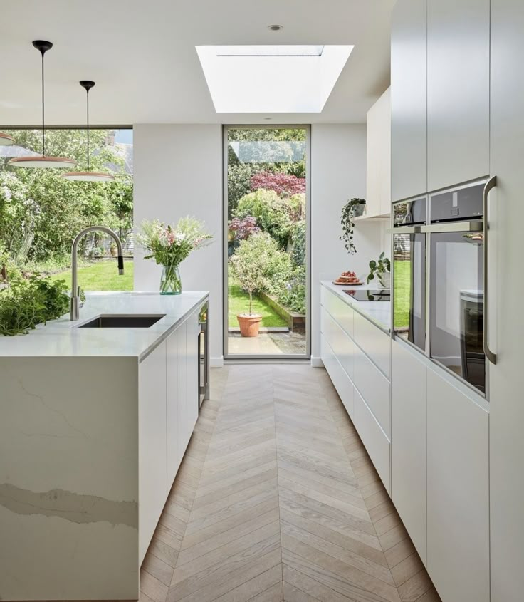 an open kitchen with white cabinets and wood flooring, along with a skylight