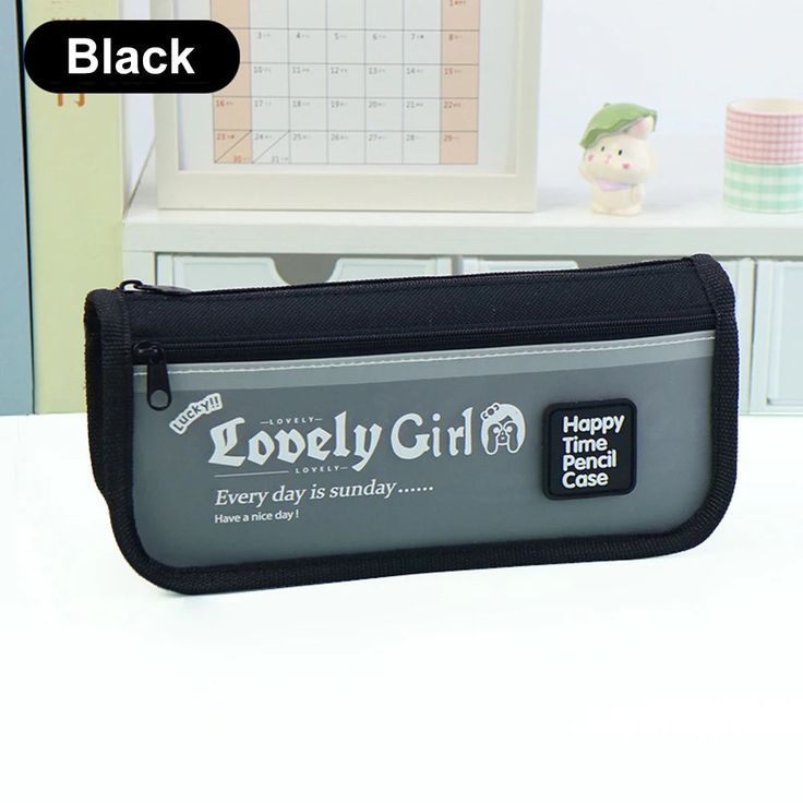 a black pencil case sitting on top of a white desk next to a computer monitor