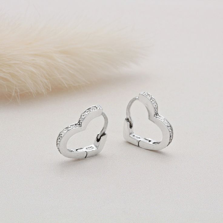 Show your jewellery collection some love and add in these beautiful heart huggie hoop earrings. Whether there is a special someone in your life whom you wish to treat or need a little pick me up, these earrings are perfect. Set with cubic zirconia stones to give them an added sparkle. They are complete with a secure click-in fastening for wearing day and night. Sure to be loved by all ages.  Internal Height: 9mm 925 Sterling Silver, Cubic Zirconia Stones Anniversary Heart-shaped Hoop Earrings With Heart Charm, Heart-shaped Sterling Silver Huggie Earrings For Anniversary, Valentine's Day Huggie Earrings For Anniversary, Valentine's Day Open Heart Huggie Earrings For Anniversary, Valentine's Day Open Heart Huggie Earrings, Valentine's Day Heart Charm Huggie Earrings For Anniversary, Valentine's Day Heart Charm Huggie Earrings, Valentine's Day Huggie Earrings With Heart Charm, Valentine's Day Huggie Heart Earrings For Anniversary