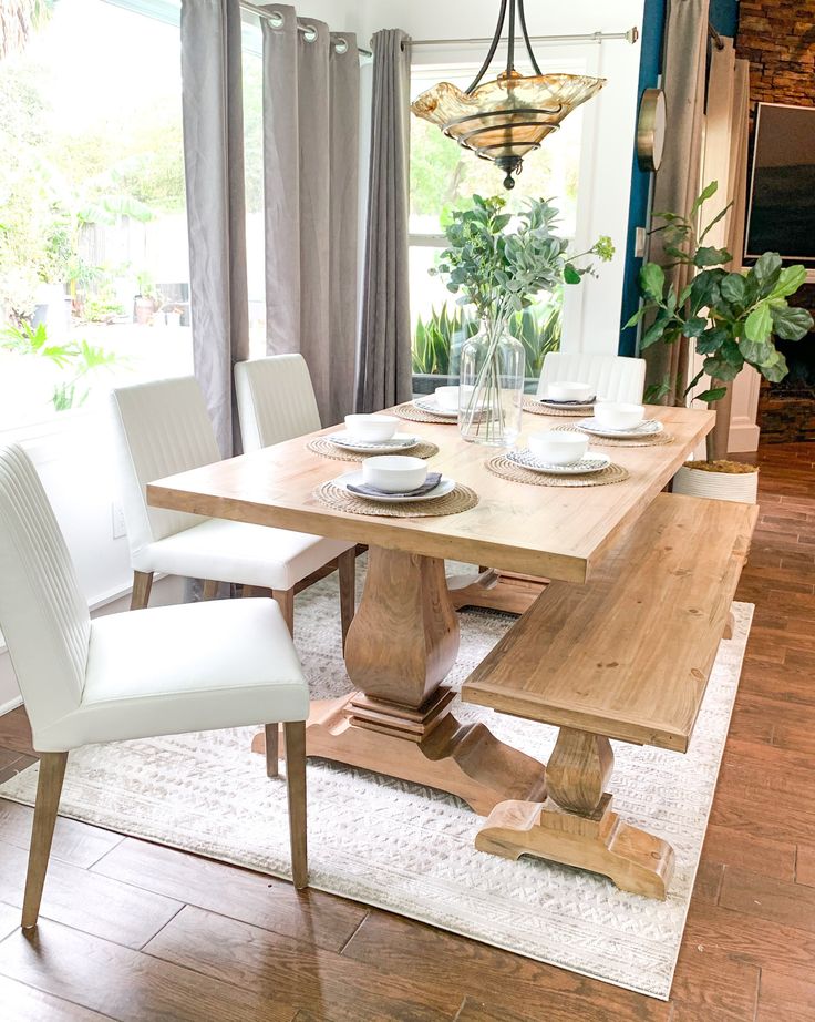 a dining room table with two white chairs and a wooden bench in front of it