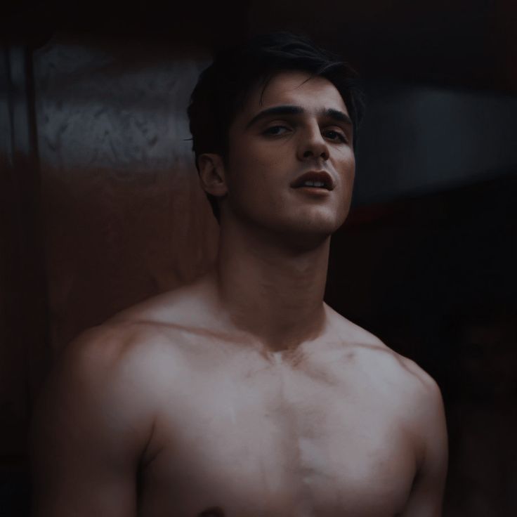 a shirtless man standing in a dark room with his eyes closed and no shirt on