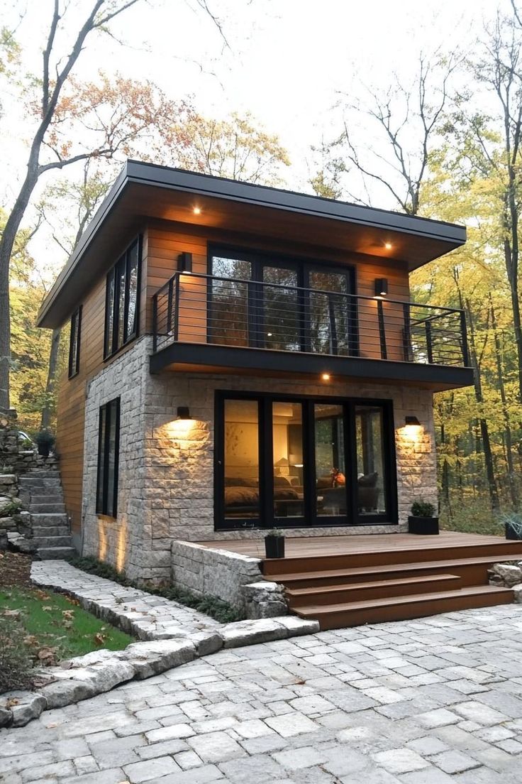 a modern house in the woods with stairs leading up to it's second story