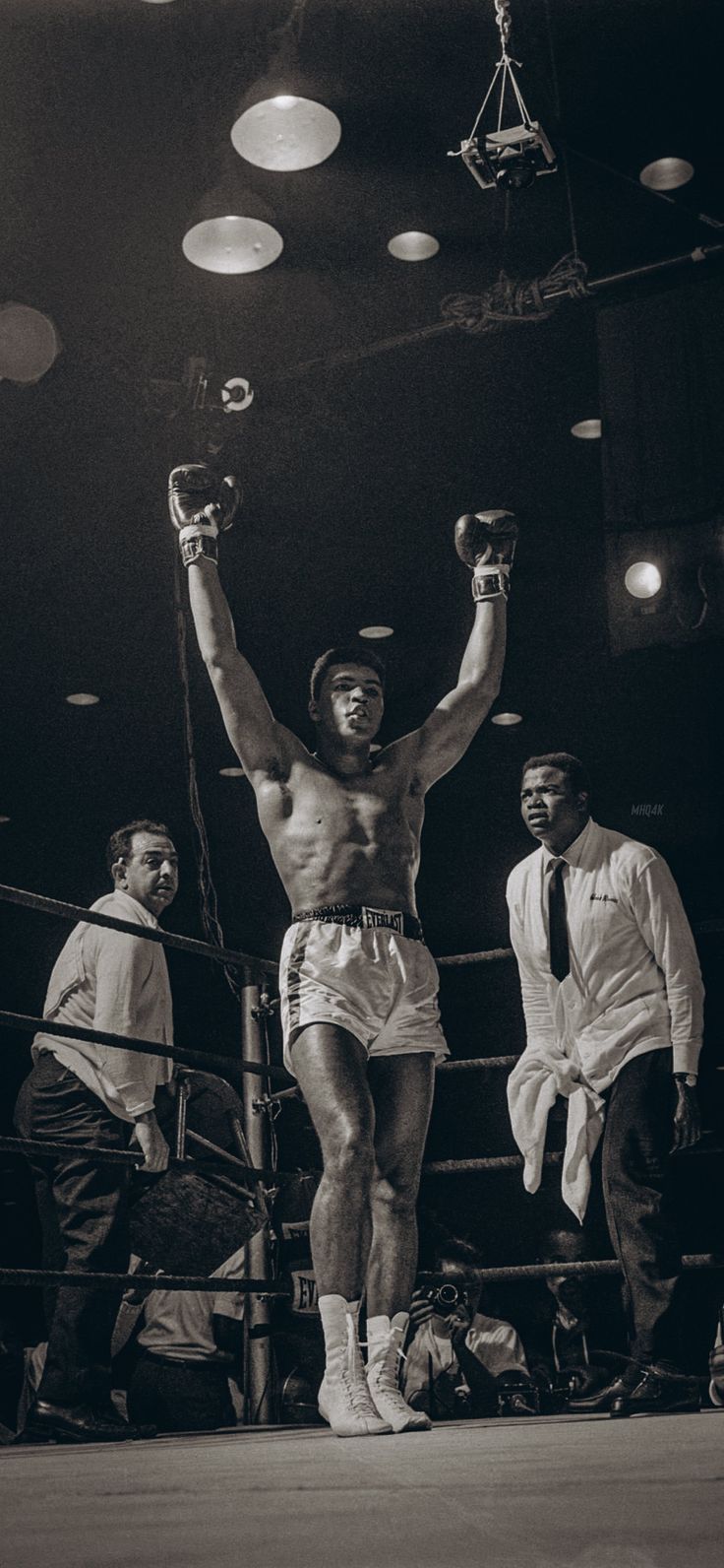 a man standing on top of a boxing ring holding up his hands in the air