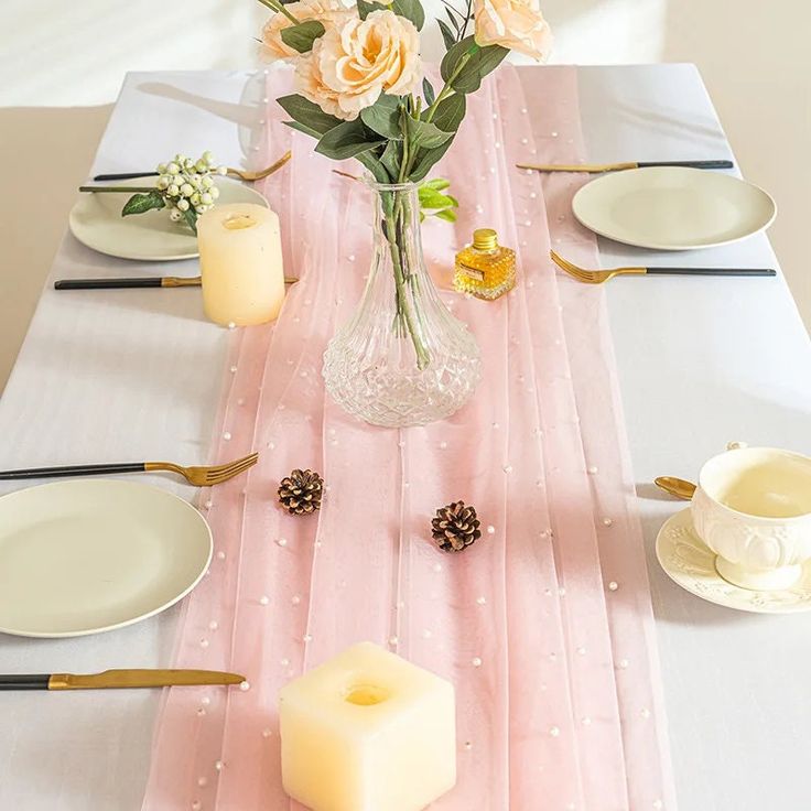 the table is set with candles, plates and flowers