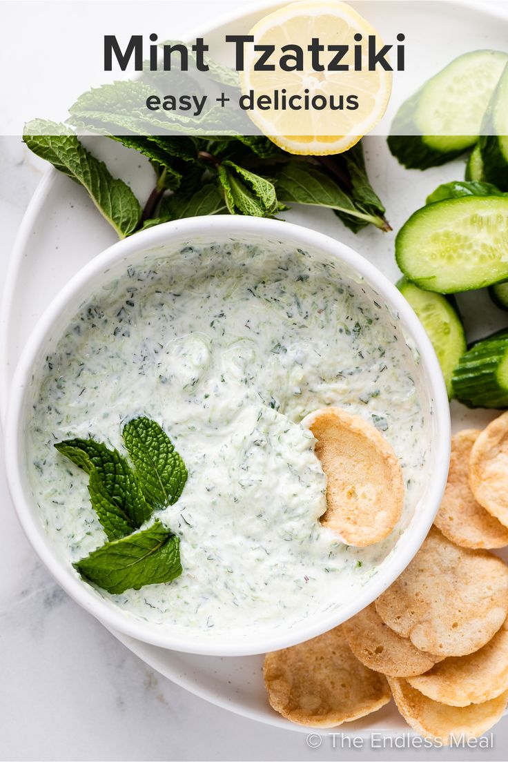 a white plate topped with cucumber chips and a bowl of minty tzatzki