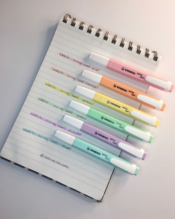 a notebook with several different colored pens on it