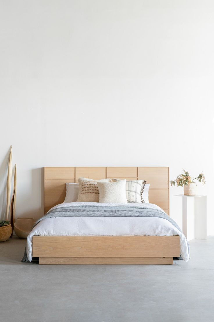 a bed sitting in the middle of a room next to a vase with flowers on it