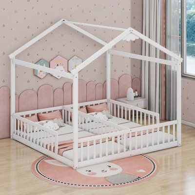 a child's bed with a white frame and pink bedspread on the floor