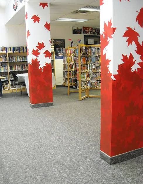 two tall red and white pillars with maple leaves painted on them in an open library