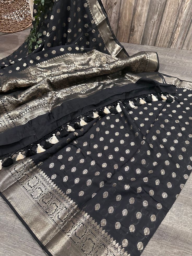 Beautiful black and light gold cotton silk Banarsi saree finished with handmade resham thread tassels. Fall attached and  brocade blouse fabric included.  Note: The color rendition of the products may vary according to the lighting conditions and the color calibration of LED devices. If you would like more clarity before your purchase, please drop us a message. Banarasi Silk Blouse Piece With Latkans For Eid, Black Raw Silk Traditional Wear For Diwali, Black Raw Silk Saree With Zari Work, Black Raw Silk Saree With Cutdana, Black Raw Silk Saree Blouse Piece, Black Raw Silk Traditional Wear With Zari Work, Black Raw Silk Saree With Pallu, Black Raw Silk Dupatta In Traditional Drape, Black Slub Silk Saree