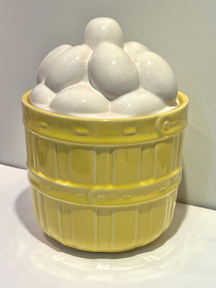 a yellow bowl filled with white balls on top of a table next to a wall