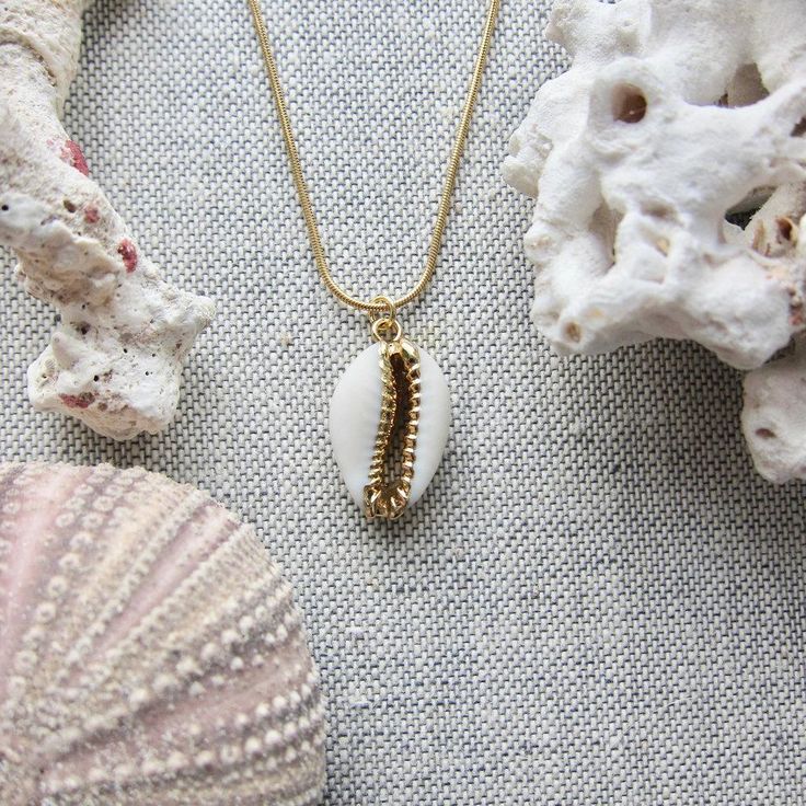 We love this fun and summery, beachy necklace. Answer the siren's song and get one for yourself or someone you love. Would make a great gift for the surfer or beach-lover in your life! A 14k gold electroplated cowrie shell dangles from a lustrous, high quality gold filled snake chain. The perfect summertime accessory! Chain length 16"✦ JEWELRY CARE ✦✧ Warm water and a soft cloth are the best thing you can do to maintain the beauty of your jewelry.✧ Jewelry polishing cloths work great and are non Gold Shell Necklace With Starfish Charm For Summer, Beachy Gold Shell Necklace For Gifts, Beachy Gold Shell Necklace As A Gift, Beachy Gold Shell Necklace For Gift, Beachy Gold Shell Necklace Perfect For Gifts, Gold Shell Necklace With Starfish Charm For Vacation, Beachy Gold Jewelry With Starfish Charm, Gold Strand Charm Necklace As Gift, Gold Strand Charm Necklace For Gift