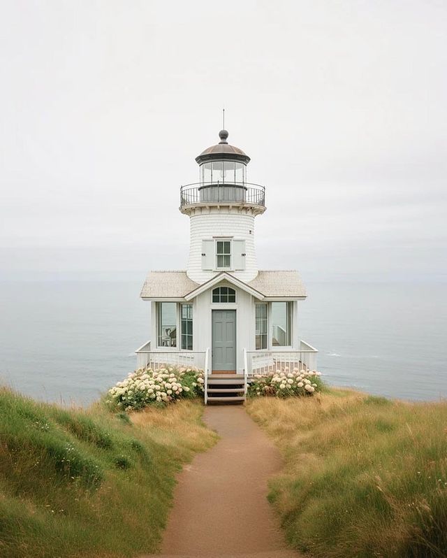 a light house on top of a grassy hill next to the ocean